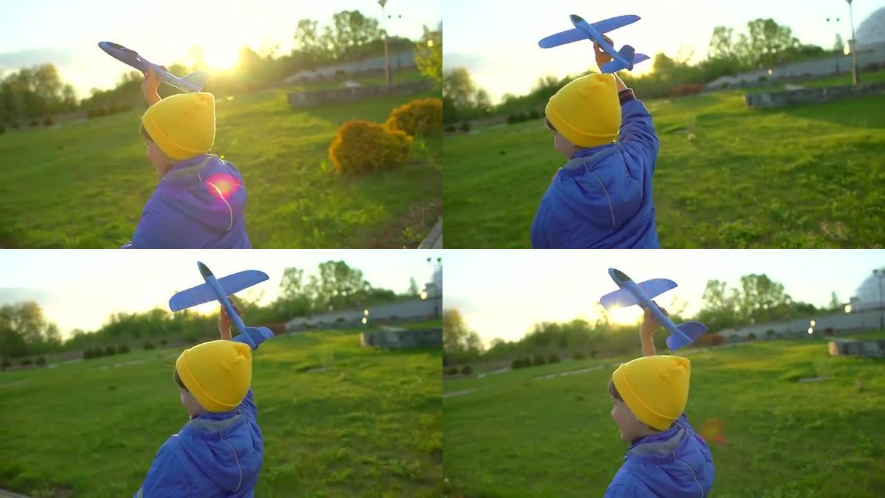 日落时，快乐的小男孩在公园里用玩具飞机跑步。孩子在户外夏天玩飞机。小飞行员梦想飞行，旅行度假幸福家庭