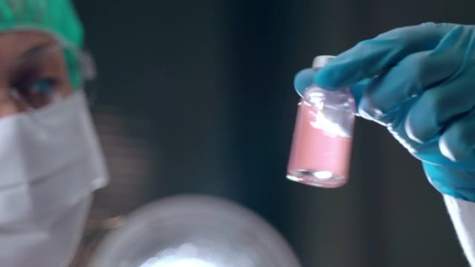 医生在实验室用红色溶液握持和摇动无菌小瓶的特写，医学科学研究开发有效的新型冠状病毒肺炎疫苗。实验室实