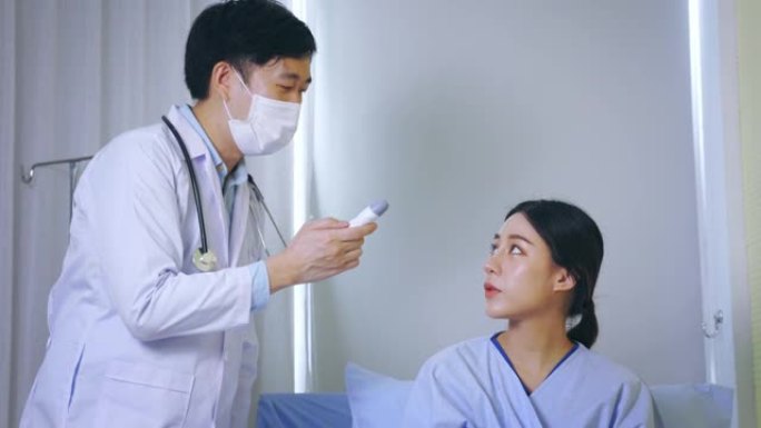 年轻男耳鼻喉科医生带听诊器在医院用鼓室温度计测温度检查穿制服的亚洲女病人
