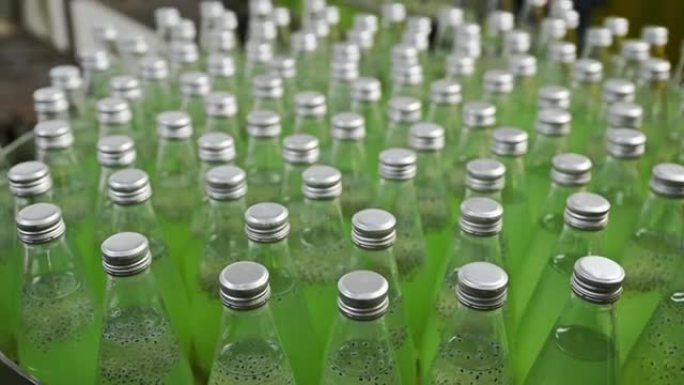 饮料加工厂生产线上的瓶装绿色果汁点心