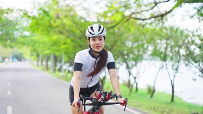 亚洲年轻美女晚上在公园骑自行车健康。运动员适合和坚定的女孩穿着运动服通过骑自行车锻炼运动来锻炼她的健