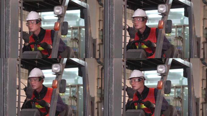 亚洲男性仓库工人在重工业制造工厂与驾驶叉车的同事通过无线电电话或对讲机交谈。努力工作的人的肖像。运输