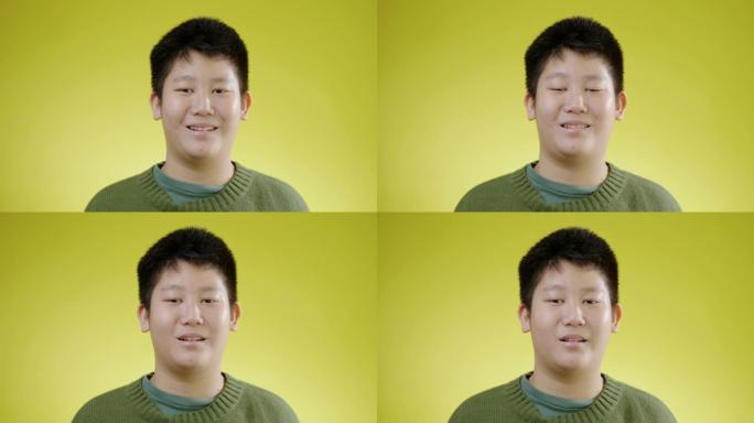 快乐的亚洲男孩微笑着看着黄色背景的相机，生活方式的概念。