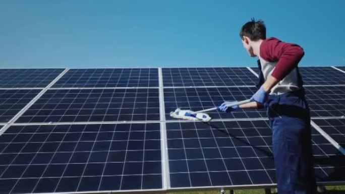 男子在家用发电厂清洗太阳能电池板的后视图