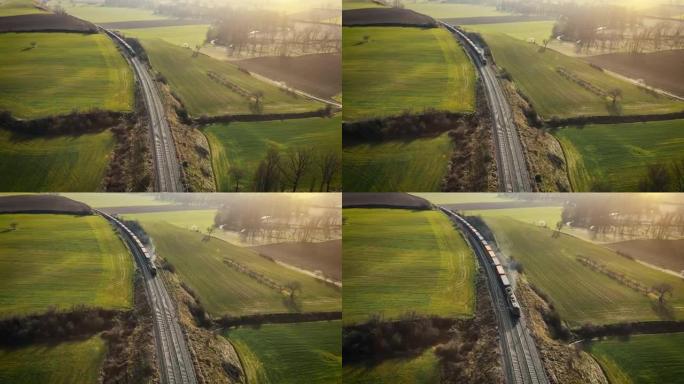 货运列车的鸟瞰图，载着五颜六色的集装箱，在日落时穿过森林。无人机拍摄的4k镜头。高质量4k镜头
