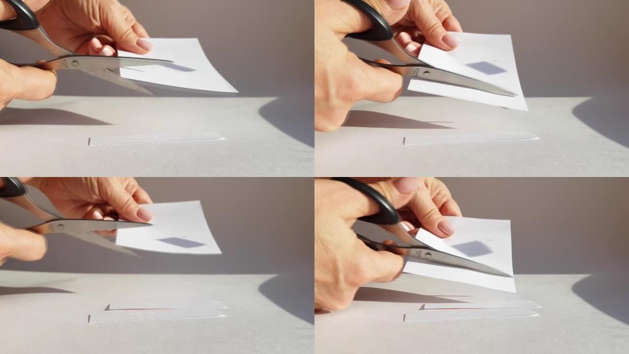 女人的手用剪刀剪一张白纸，剪掉边角。特写，DIY概念