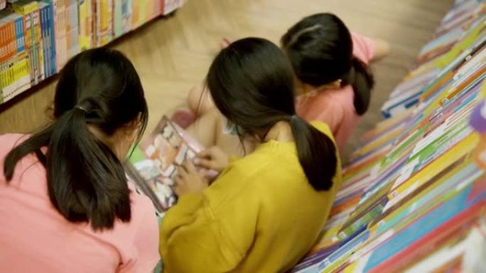 快乐的亚洲儿童看书，一起坐在书店的地板上，生活理念。