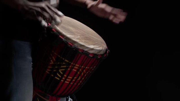 黑人在演播室用手近距离打鼓。音乐家在黑暗中演奏传统的非洲鼓。艺术家节拍节奏