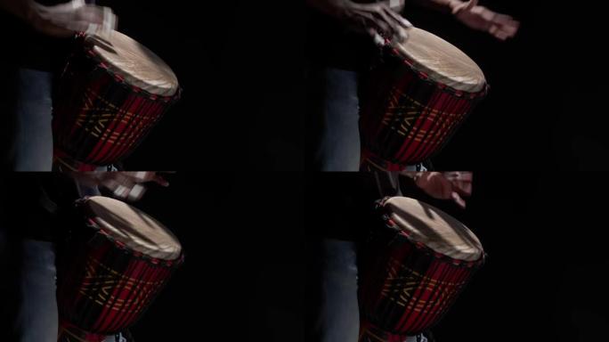 黑人在演播室用手近距离打鼓。音乐家在黑暗中演奏传统的非洲鼓。艺术家节拍节奏