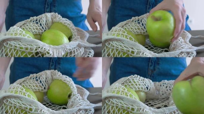 水果白网。网里有很大的青苹果。用左手打开网，一个接一个地给苹果。健康饮食。水果有用性概念