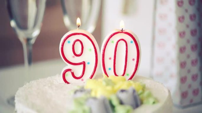 生日蜡烛作为90号90在桌上的甜蛋糕上，90岁生日，调子视频