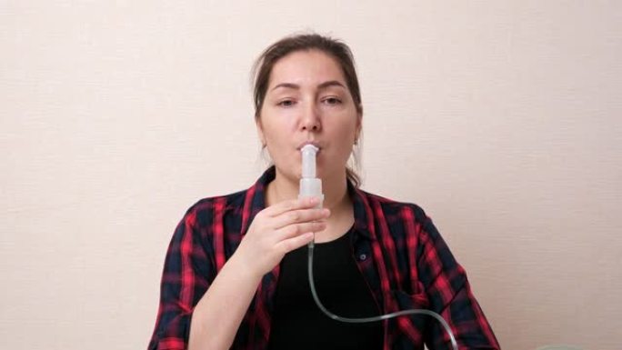 黑发女人用口腔雾化器管呼吸蒸汽
