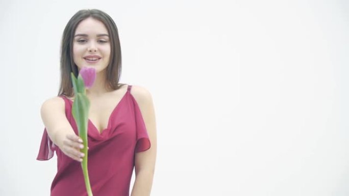 激动女人的4k视频在春季女性假期之际与一堆郁金香站在一起。