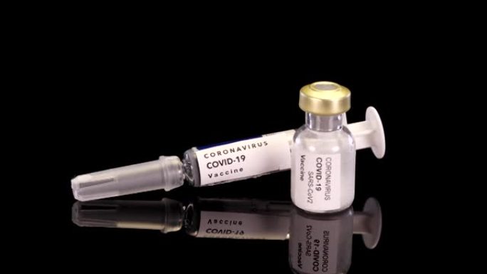 冠状病毒疫苗在安瓿和注射器旋转在黑色背景。疫苗新型冠状病毒肺炎病毒概念。安瓿配疫苗。冠状病毒大流行的