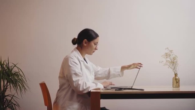 女医生刚刚结束工作。她从桌子上站起来，关上笔记本电脑离开。