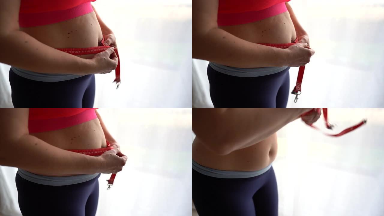 关闭沮丧的超重妇女测量腰部。绝望地扔卷尺，因体重过重而沮丧，产后恢复