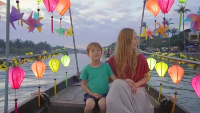 一名年轻女子和她的儿子游客参观了越南中部的一个古老城镇会安。他们正在乘船游览装饰着发光的五颜六色的灯