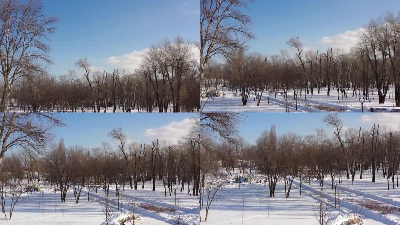 鸟瞰图。冬天阳光明媚的寒冷日子里，城市公园在雪地里。与人，树木，阴影和路径一起停车