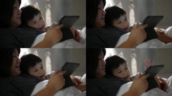 亚洲孩子和母亲使用数字平板电脑玩游戏。家庭时间时刻的概念