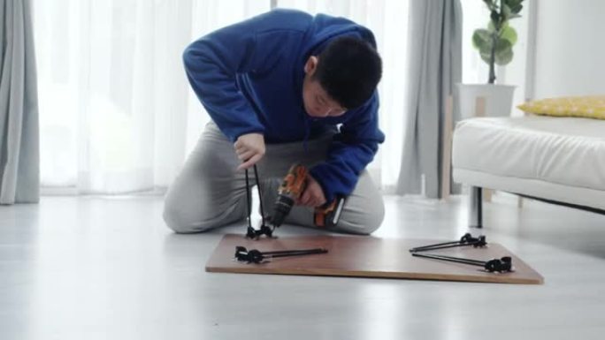 亚洲男孩在家里窗户附近的地板上修理破桌子，生活方式的概念。