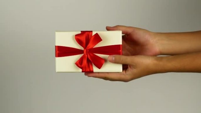 一个男人给一个女人一个圣诞快乐的礼物。新年和圣诞节礼物装在明亮的盒子里，带有惊喜的蝴蝶结。礼品盒特写