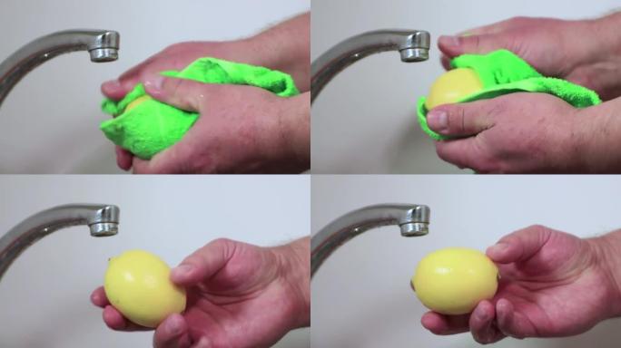 男性双手用绿色毛巾擦干黄色柠檬。