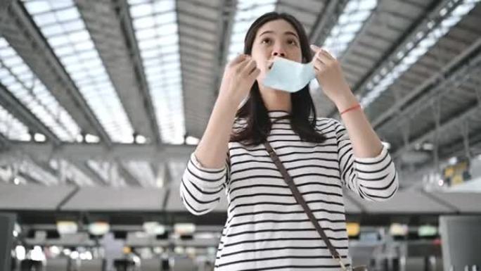 新常态、安全和旅行运输亚洲妇女在机场拿着手提行李后用酒精手清洁手扎尼泽，戴着防护口罩保护泰国曼谷冠状