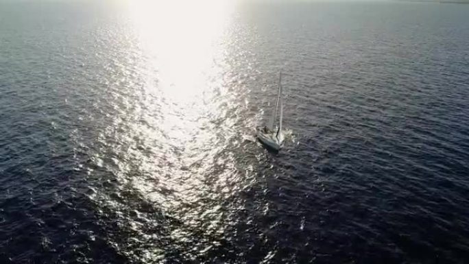 在阳光下在地中海中部航行的帆船的鸟瞰图。我们可以看到整个地平线上的船和水以及水中光线的反射4K