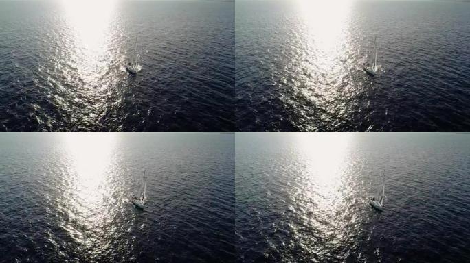 在阳光下在地中海中部航行的帆船的鸟瞰图。我们可以看到整个地平线上的船和水以及水中光线的反射4K