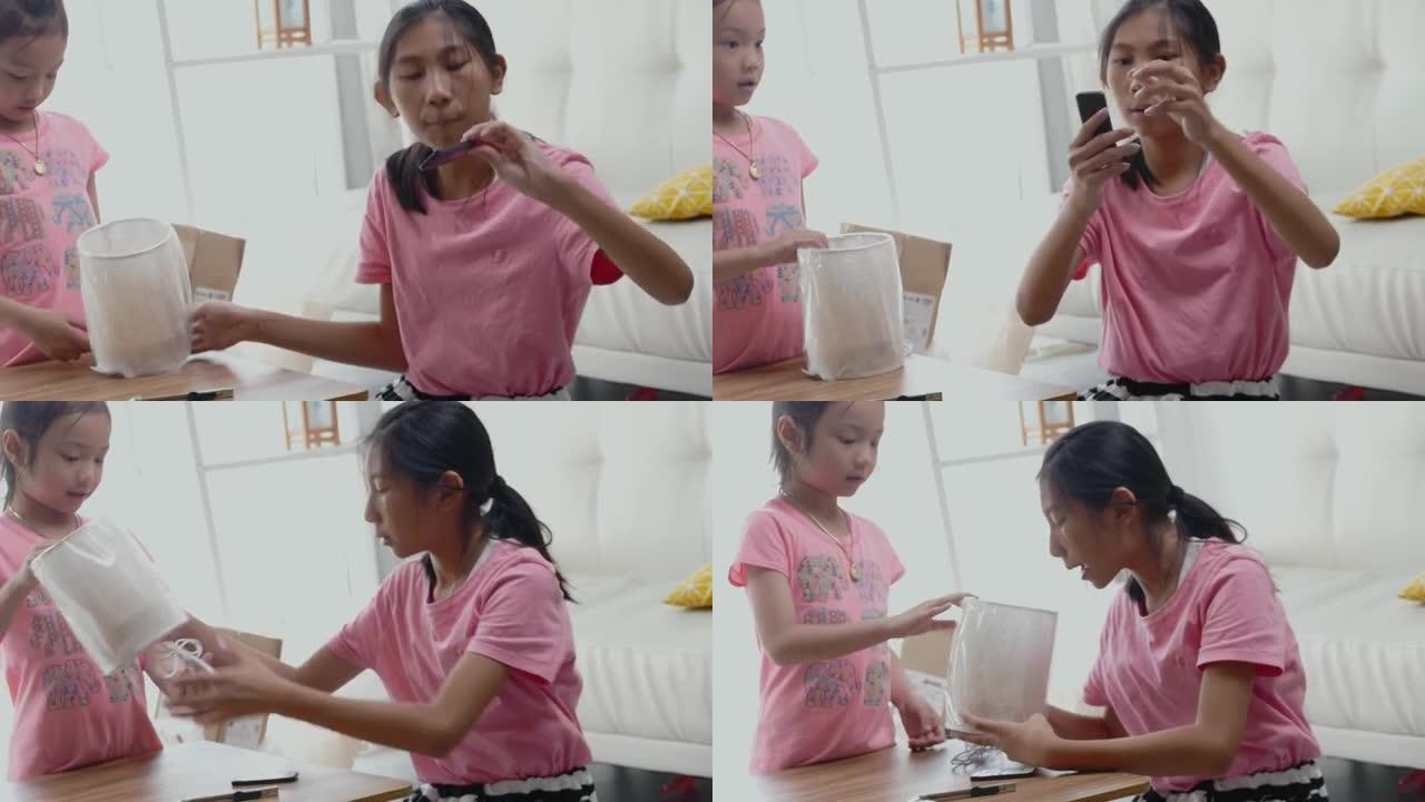 快乐的亚洲儿童收到网上购物的商品，并在家里打开窗户附近的新电灯，生活方式概念。