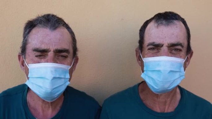 高级双胞胎男子戴着安全口罩为冠状病毒爆发而面带微笑