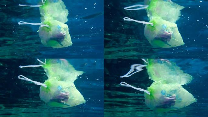 慢动作，一个装满塑料和其他杂物的塑料袋在蓝色的水中缓慢地漂移到地表以下。从船上扔出的垃圾塑料袋。红海