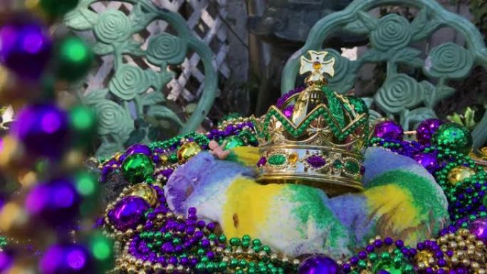Mardi Gras国王蛋糕用串珠围起来，蛋糕上戴着皇冠，小婴儿被五颜六色的珠子围起来