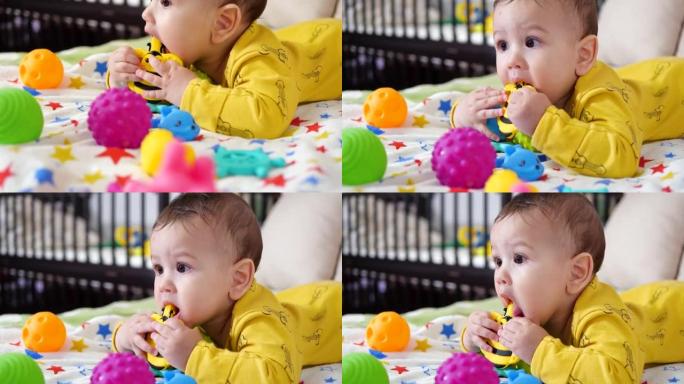 婴儿，童年的概念-微笑快乐的婴儿玩牙器的特写镜头。牙齿切割。第一颗牙齿。欢乐无牙7个月婴儿咬伤，咬牙