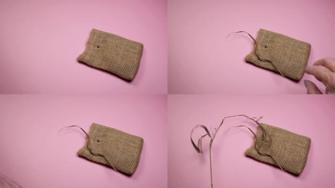 花店的手准备干草和帆布袋组成，粉红色背景，DIY概念，4k视频