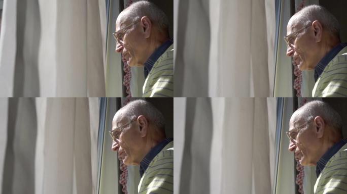 戴着眼镜的秃头老人透过窗帘透过窗户看