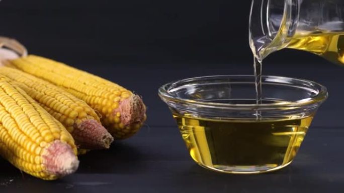 将玉米油倒入玻璃瓶中，并在质朴的背景下将玉米粒和玉米粒干燥。食用油成分