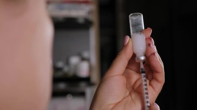 一名妇女将正确剂量的胰岛素拨入注射器的特写镜头。