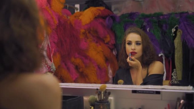 女演员漂亮女孩在更衣室的镜子前用红色唇膏画嘴唇，化妆