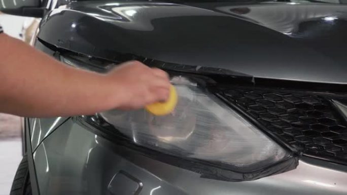 服务人员的加速镜头用手擦亮汽车前灯。汽车细节概念