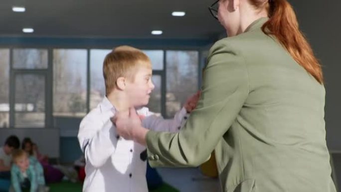 患有唐氏综合症的活跃男孩在蹦床上跳，牵着老师的手，帮助和支持残疾儿童