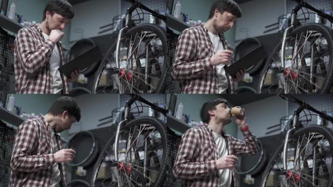 工作时午休。自行车车间机械工程师累了，在自行车维修和服务车间工作休息时吃蛋白质能量棒和喝咖啡。吃巧克