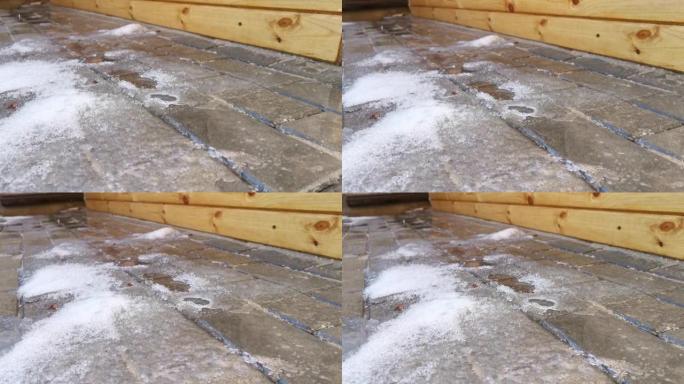 水从屋顶滴落到雪地和人行道上。