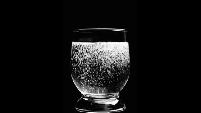 水被倒入黑色背景上的玻璃杯中