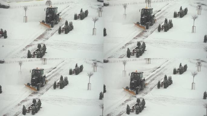 拖拉机-挖掘机清除城市院子里的积雪。公用事业的工作