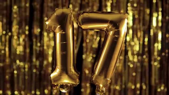 黄色背景上的充气气球上的金色数字17十七。一组完整的数字。生日、周年纪念日、日期的概念