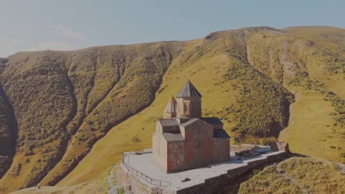 以高加索山脉为背景的山上卡兹贝吉三一教堂周围的慢动作空中圈。历史遗迹和格鲁吉亚文化概念