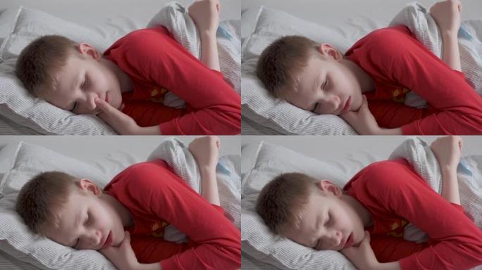 生病的十几岁的男孩，嘴唇干裂，躺在床上，咳嗽。