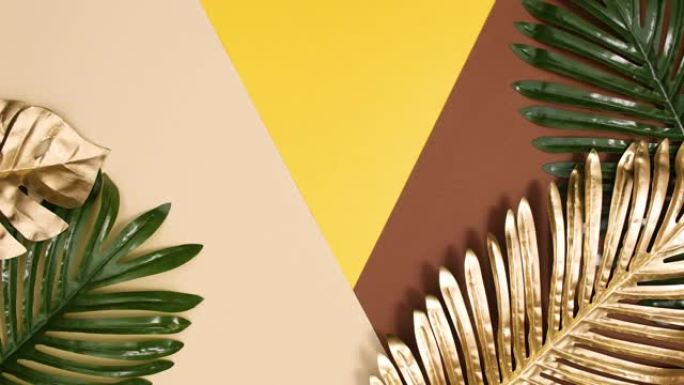热带的金色和绿色棕榈叶出现在金色的裸色背景上。定格运动平铺异域概念