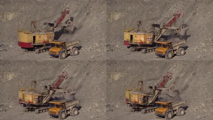 一辆巨大的采矿挖掘机将土壤倒入一辆大型多吨黄色采矿卡车的车身中